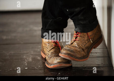 Close up of a man's pieds, portant des chaussures marron avec des lacets rouges. Banque D'Images