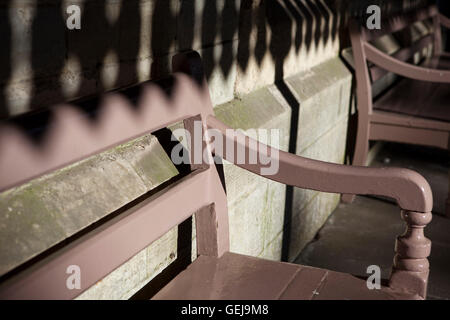 Un vieux banc en bois peint en soleil et d'ombre, sur une plate-forme de station vide. Banque D'Images