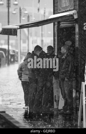 Un groupe de personnes à l'abri de la pluie sous un auvent Banque D'Images