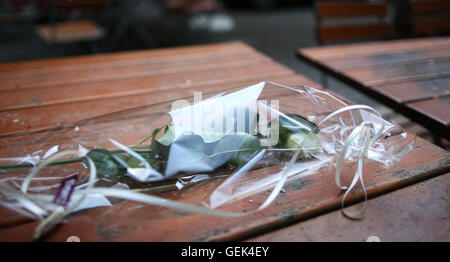 Ansbach, Allemagne. 26 juillet, 2016. Une rose blanche dans du cellophane se trouve sur une table sur le site de l'attaque dans la cour de 'Eugen's Weinstube' à Ansbach, Allemagne, 26 juillet 2016. 15 personnes ont été blessées dans une attaque motivée-islamistes présumés le 24 juillet 2016. L'auteur présumé, un homme de 27 ans pour les réfugiés en provenance de Syrie, a été tué dans l'explosion. Photo : DANIEL KARMANN/dpa/Alamy Live News Banque D'Images