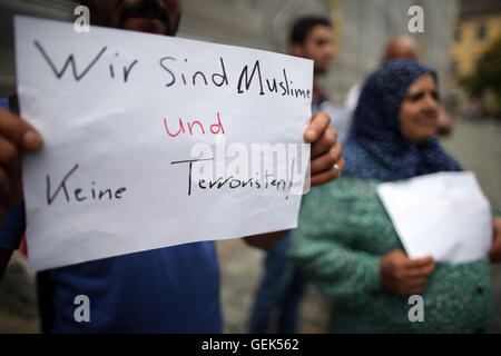 Ansbach, Allemagne. 26 juillet, 2016. Les réfugiés en provenance de Syrie se tiennent près de l'emplacement de l'attaque et tenir une pancarte avec écrit "Nous sommes des musulmans et pas des terroristes' à Ansbach, Allemagne, 26 juillet 2016. 15 personnes ont été blessées dans une attaque motivée-islamistes présumés le 24 juillet 2016. L'auteur présumé, un homme de 27 ans pour les réfugiés en provenance de Syrie, a été tué dans l'explosion. Photo : DANIEL KARMANN/dpa/Alamy Live News Banque D'Images