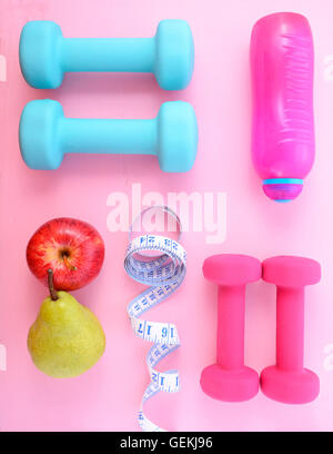 Télévision et de remise en forme avec les Dumbells rose et bleu et accessoires sur une table en bois de rose. Banque D'Images