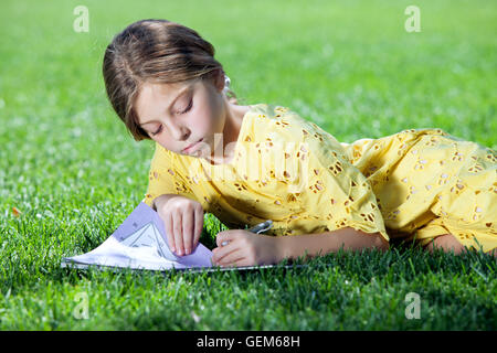 Portrait de petite fille l'étude sur l'herbe en été environnement Banque D'Images