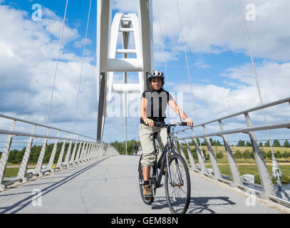 Cycliste féminine sur l'Infini pont enjambant la rivière Tees à Stockton on Tees près de Middlesbrough, Angleterre du Nord-Est. UK Banque D'Images