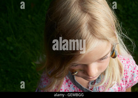 Portrait of cute blonde enfant fille avec escargot sur son visage Banque D'Images