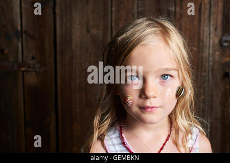 Portrait of cute blonde enfant fille avec escargot sur son visage Banque D'Images