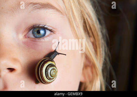 Portrait of cute blonde enfant fille avec escargot sur son visage Banque D'Images