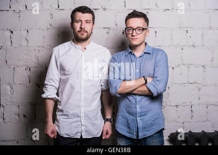 Deux jeunes hommes startupers sur mur de brique gris loft interior design Banque D'Images