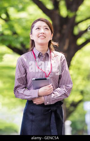 Business Woman walking along avec tree-lined road Banque D'Images