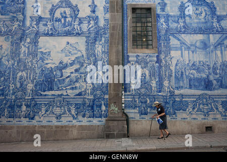 Les luttes d'une dame avec des bâtons sous tuiles azulejo traditionnel sur le mur de Capela Das Almas (église), sur la Rua Santa Catarina Banque D'Images