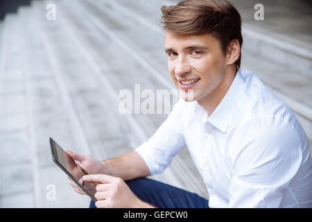 Portrait of happy handsome young businessman using tablet outdoors Banque D'Images