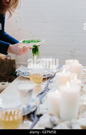 Une femme en plaçant un plateau de nourriture sur une table décorée avec des bougies allumées. Banque D'Images