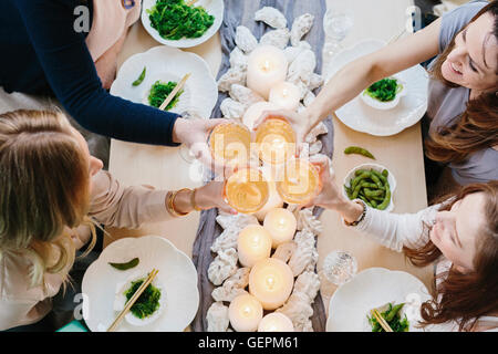 Vue de dessus de quatre personnes partageant un repas, plateaux de sushis et une table pour un repas de fête. Banque D'Images