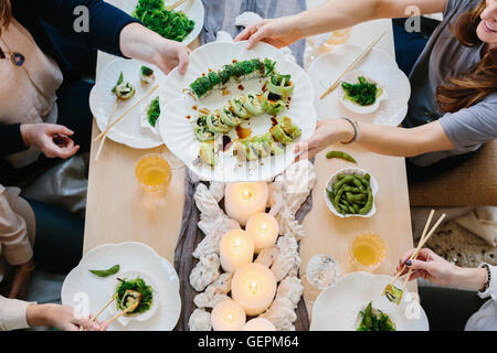 Vue de dessus de quatre personnes partageant un repas, plateaux de sushis et une table pour un repas de fête. Banque D'Images