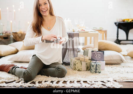 Une femme assise sur le sol tenant une gift wrapped present. Banque D'Images