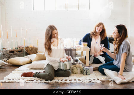 Trois femmes lors d'une célébration, une ouverture d'une pile de cadeaux. Banque D'Images