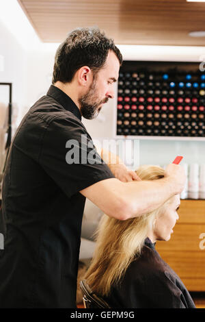Un coiffeur à peigner les cheveux d'un client. Banque D'Images