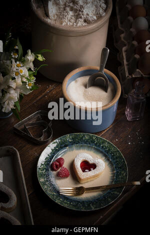 La Saint-Valentin, high angle view of un bol de sucre et une plaque avec des biscuits en forme de cœur et de framboises fraîches. Banque D'Images