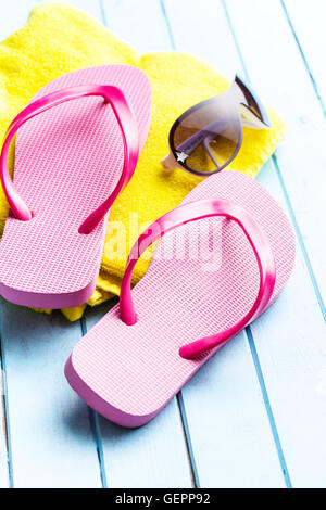 Tongs roses avec une serviette et des lunettes de soleil. Banque D'Images