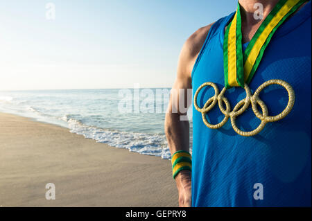 RIO DE JANEIRO - le 10 mars 2016 : Athlète portant des anneaux olympiques médaille d'élève face à Sunrise Beach shore. Banque D'Images