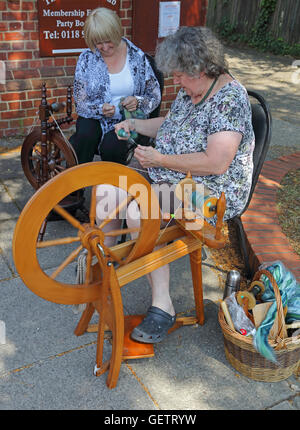 Deux dames assis par leurs rouets 'teasing' out la laine prêt à aller sur la roue qui tourne pour faire la laine. Banque D'Images