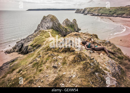 Une femme afro antillais détente sur trois collines surplombant la baie d'Clffs sur le Gower. Banque D'Images