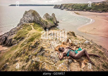 Une femme afro antillais détente sur trois collines surplombant la baie d'Clffs sur le Gower. Banque D'Images