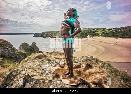 Une femme afro antillais détente sur trois collines surplombant la baie d'Clffs sur le Gower. Banque D'Images