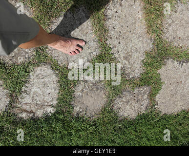 Homme marchant pieds nus sur les pierres de l'ancienne voie romaine d'aller à Rome en Italie Banque D'Images