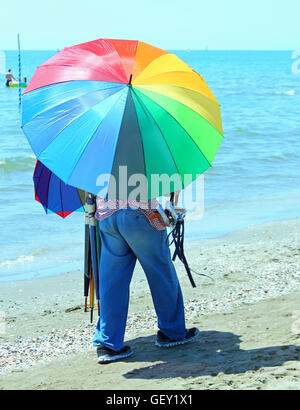 Pauvre colporteur de parasols sur la plage en été Banque D'Images