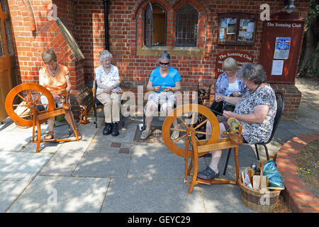 Un groupe de femmes assises autour alors que certains d'entre eux fils de spin sur des rouets en dehors de l'ancienne salle des fêtes. Banque D'Images