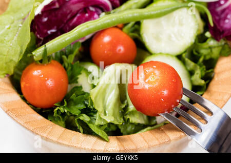 Vue rapprochée de la tomate cerise et la fourche avec bol de salade en arrière-plan. Selective focus sur l'avant avec la fourchette de tomate Banque D'Images