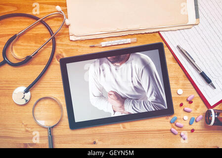 Ordinateur tablette avec photo de l'homme ayant des douleurs dans l'abdomen sur le bureau du médecin 24, vue d'en haut Banque D'Images