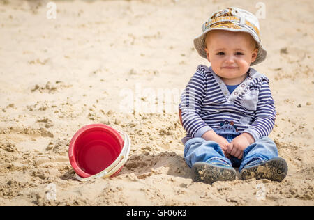 Adorable petit garçon assis dans un bac à sable dans une aire de jeux extérieure Banque D'Images