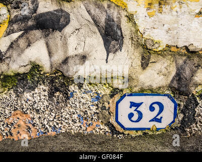 Vieille porte plaque avec le numéro 32 sur un mur d'une ancienne maison Banque D'Images