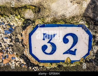 Vieille porte plaque avec le numéro 32 sur un mur d'une ancienne maison Banque D'Images