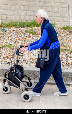 Une femme âgée marcher avec un3903 aide à la marche, Rottingdean, Sussex, UK Banque D'Images