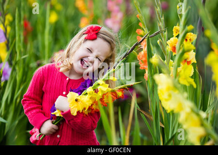 Little girl holding glaïeul fleurs''. Préparation de l'enfant des fleurs fraîches dans le jardin. Jardinage Enfants en automne Banque D'Images