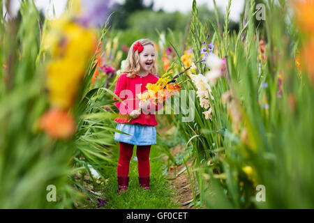 Little girl holding glaïeul fleurs''. Préparation de l'enfant des fleurs fraîches dans le jardin. Jardinage Enfants en automne Banque D'Images