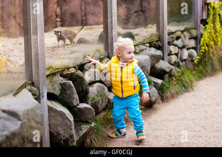 Petit garçon, mignon tout-petit enfant regardant hyène dans le zoo sur une froide journée d'automne. Enfant à la recherche sur les animaux au parc safari. Banque D'Images