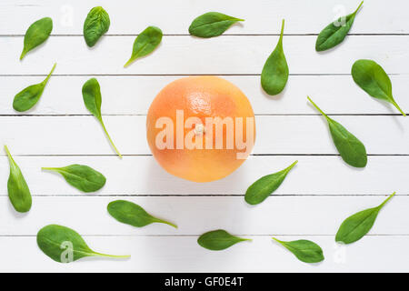 Motif fruits. Les feuilles d'épinards et pamplemousse rouge sur blanc des planches en arrière-plan. Mise à plat des frais sain ingrédients alimentaires. Banque D'Images