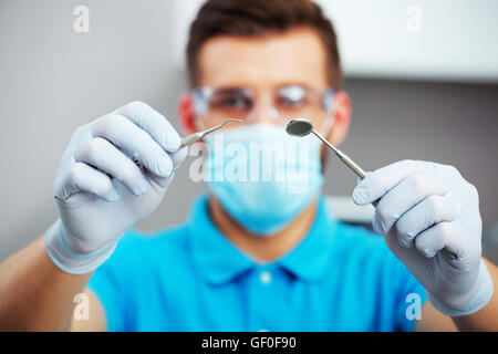 Dentiste en masque et lunettes de protection dentaire prêt à commencer l'examen de santé. Se concentrer sur les mains. Banque D'Images
