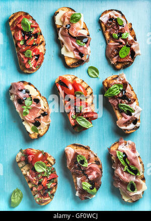 Brushetta définie pour le vin. Variété de petits sandwiches sur fond bleu turquoise, vue du dessus Banque D'Images