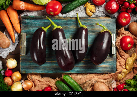 Grand frais aubergines close-up entre cadre fabriqué à partir de légumes mûrs sur fond de bois. Vue d'en haut. Les aubergines, le chou, les carottes. Banque D'Images