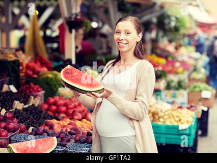 Pregnant woman holding watermelon at street market Banque D'Images