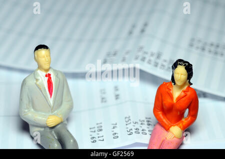 L'homme et la femme miniature assis sur la masse salariale Banque D'Images