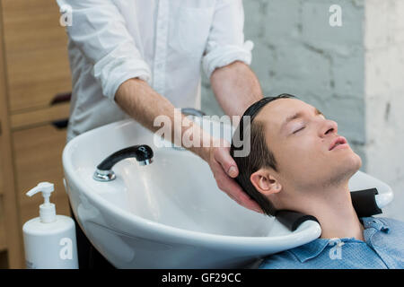 Vue de profil d'un jeune homme se préparer pour ses cheveux lavés Banque D'Images