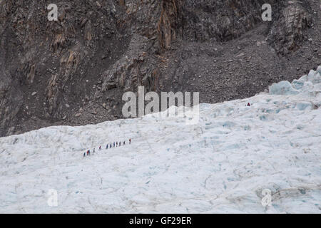 Franz Josef, Nouvelle-Zélande - 22 mars 2015 : un groupe de touristes en randonnée dans la distance sur glacier Franz Josef. Banque D'Images