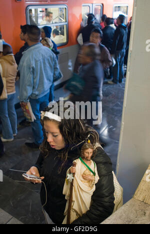 Une jeune femme, portant une statue de saint Jude Thaddée, le saint patron des causes perdues, attend à bord du métro de Mexico City Banque D'Images