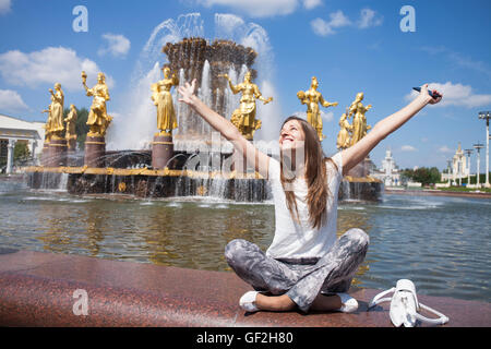 Belle jeune femme a un reste assis près de la fontaine de l'amitié du peuple vue par jour à VDNKH - exposition à Moscou, Banque D'Images